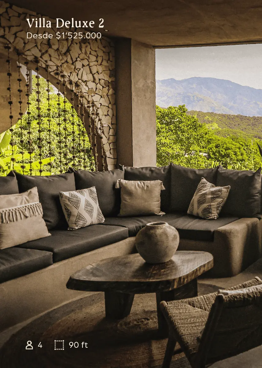 Cozy outdoor living area with a dark sectional sofa, patterned cushions, and a wooden coffee table overlooking mountainous scenery.